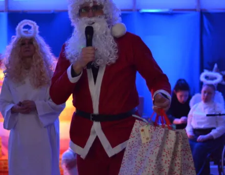 21. Nauczyciel przebrany za Świętego Mikołaja trzyma w ręku prezenty dla uczniów