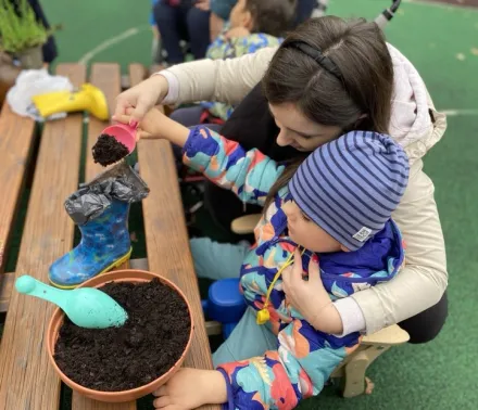 Alex z pomocą Pani Wiktorii wsypuje ziemię do kalosza