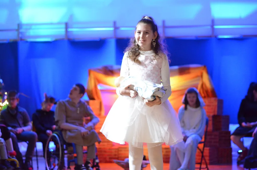 10 Uczennica ubrana w białą sukienkę niesie małego Jezusa do żłóbka