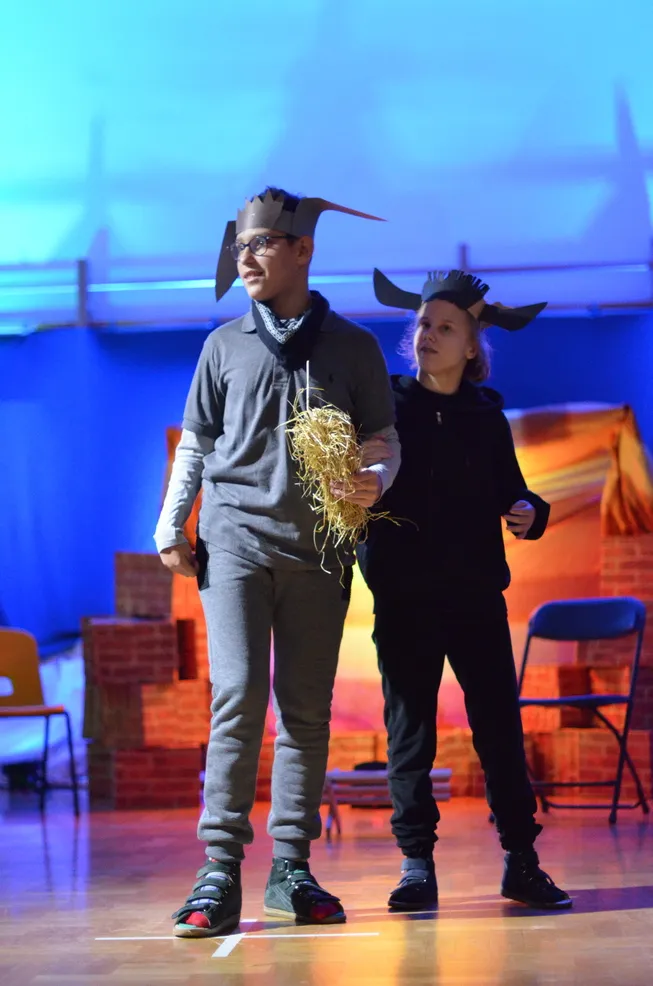 3. Na tle szopki stoi przebrany za osła chłopiec. Uczeń trzyma w ręku sianko. Obok Niego stoi dziewczynka, która ma na głowie opaskę z rogami krowy