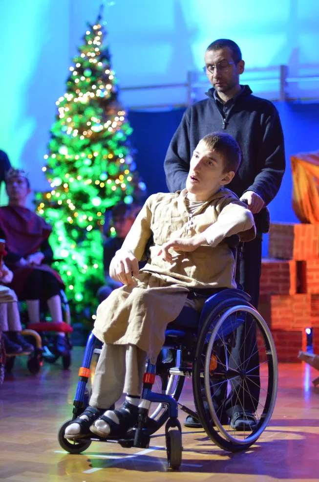 8. Uczeń grający w Jasełkach Józefa stoi z Panem Asystentem na tle szopki i choinki