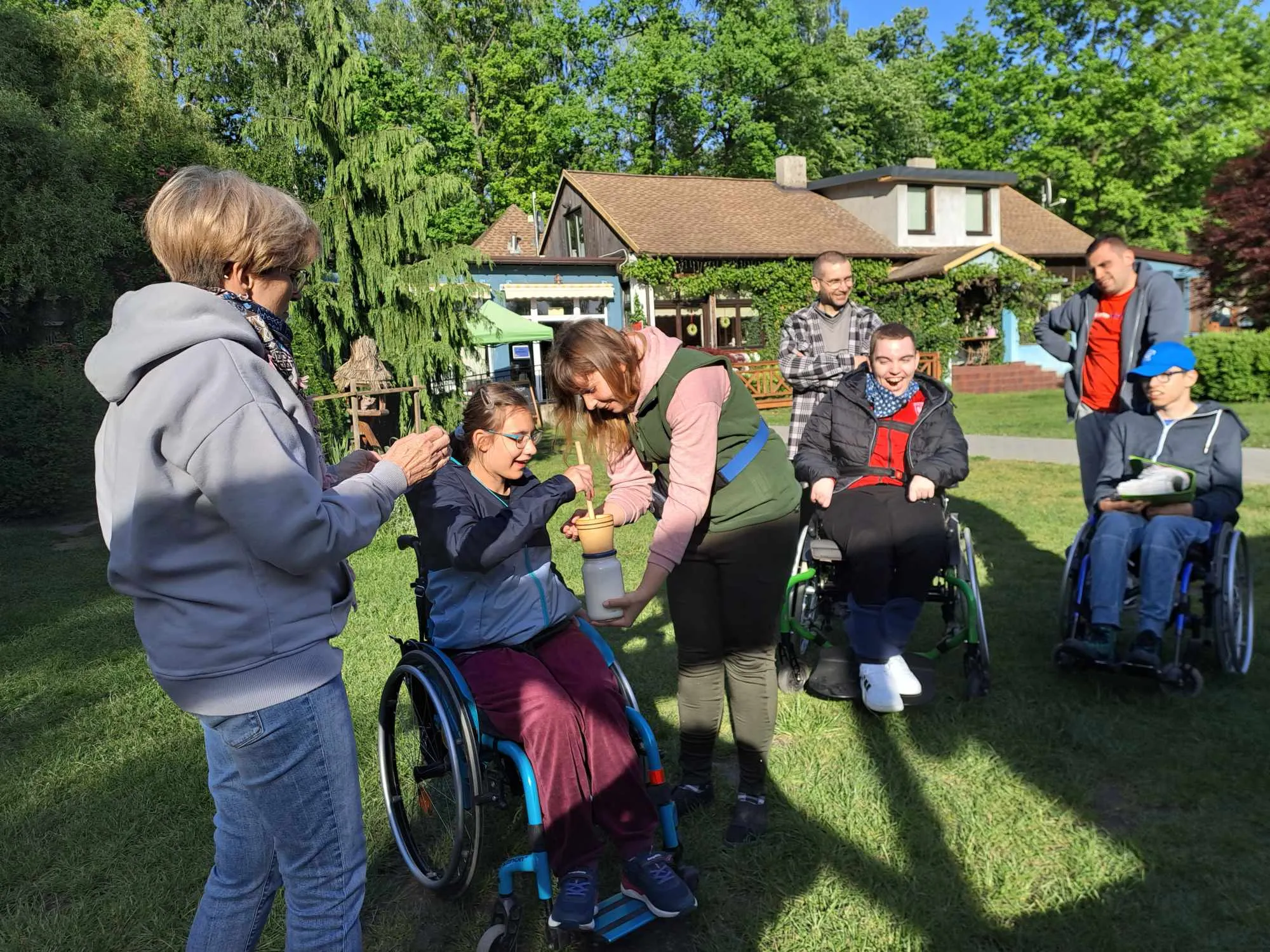 Uczennica robi masło. Koledzy i dorośli patrzą na dziewczynkę