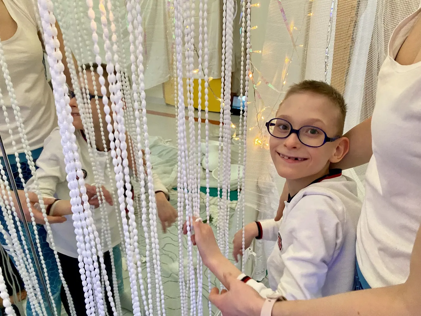 Karol uśmiecha się podczas zabawy białymi frędzlami